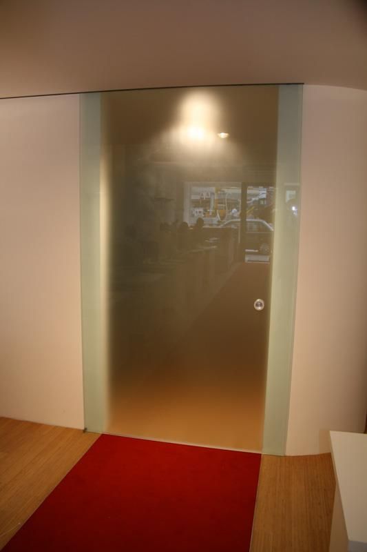 Eine Glasschiebetür mit einem roten Teppich davor.