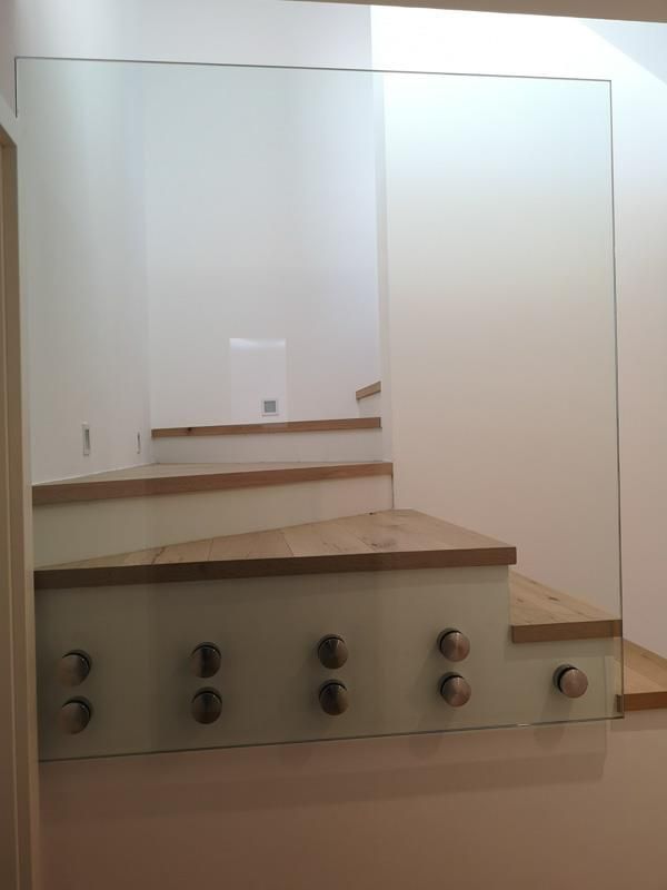 Eine Treppe mit Glasgeländer und Holzstufen.