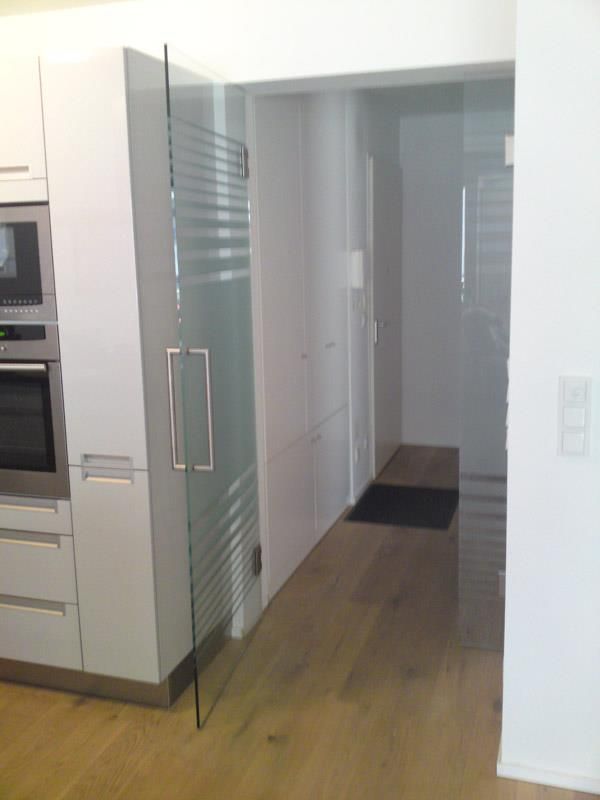 Eine Küche mit weißen Schränken und einer Glastür