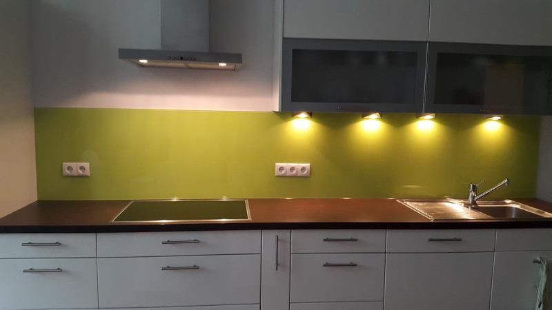 Eine Küche mit weißen Schränken und einer grünen Küchenrückwand