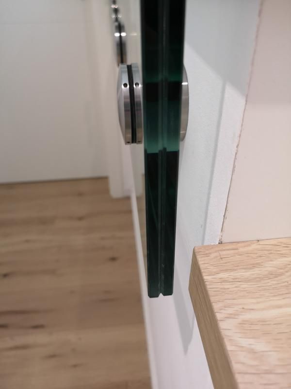 Eine Nahaufnahme eines Glasgeländers einer Holztreppe.