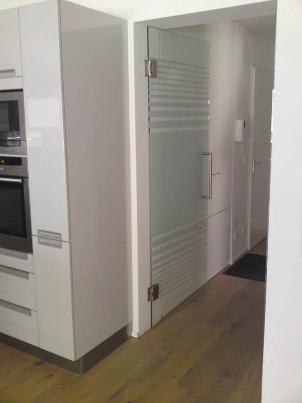 Eine Küche mit weißen Schränken und einer Glastür