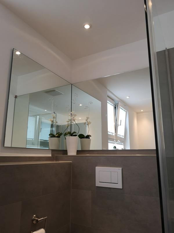 Ein Badezimmer mit einem großen Spiegel an der Wand