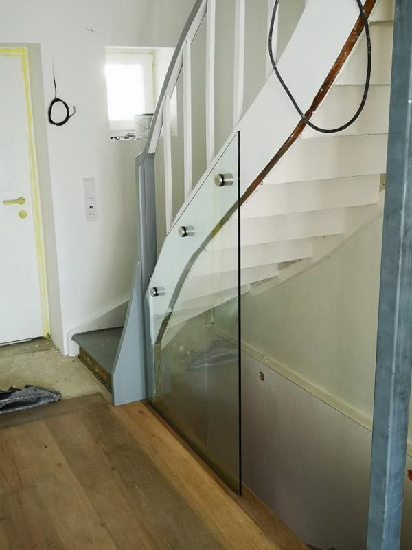 Eine weiße Treppe mit einem Glasgeländer in einem Flur.