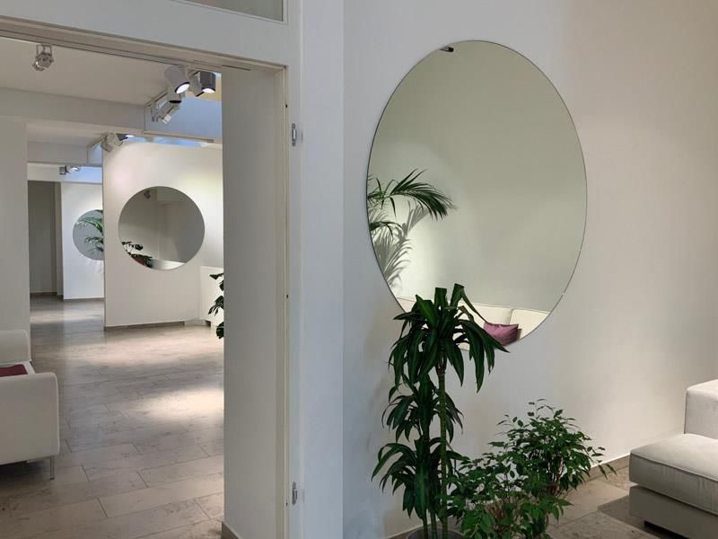 Ein großer, runder Spiegel hängt an einer weißen Wand in einem Wohnzimmer.