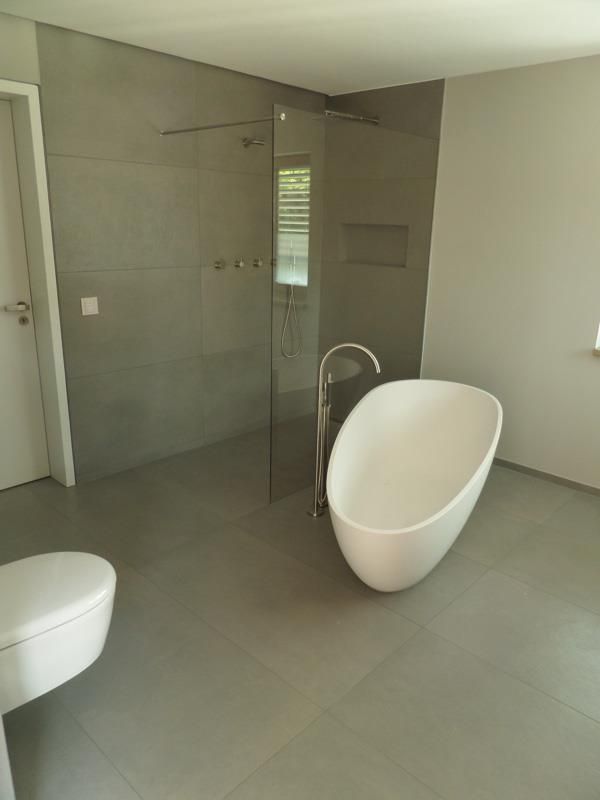 Ein Badezimmer mit Badewanne, Toilette und ebenerdiger Dusche.