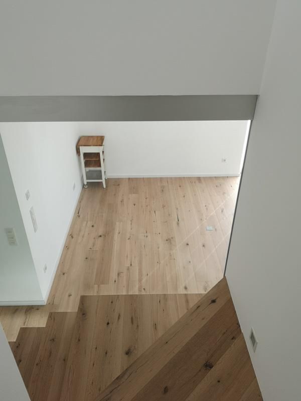 Ein Blick auf einen Raum vom oberen Ende einer Holztreppe aus.