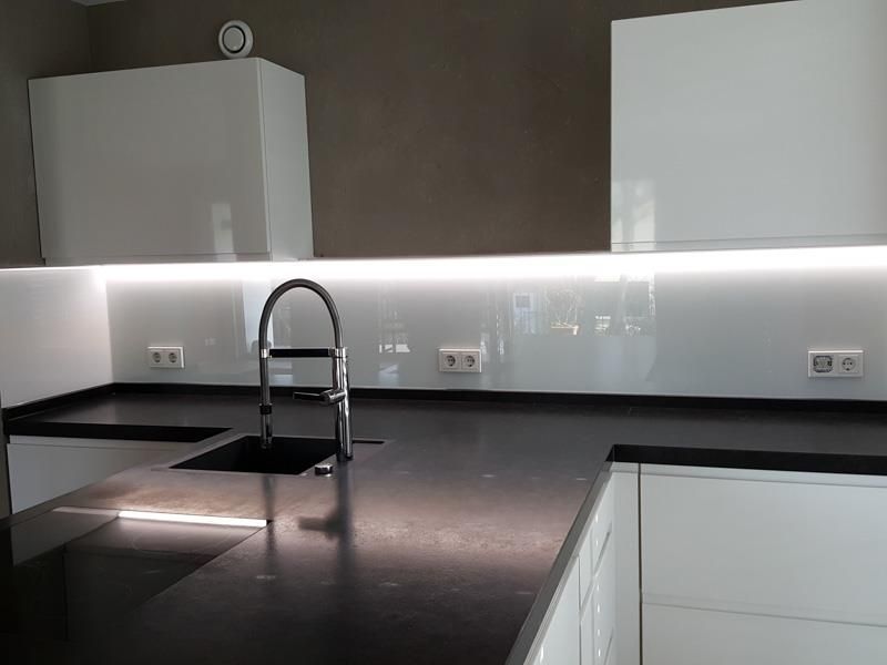 Eine Küche mit weißen Schränken, schwarzen Arbeitsplatten, einer Spüle und einem Wasserhahn.