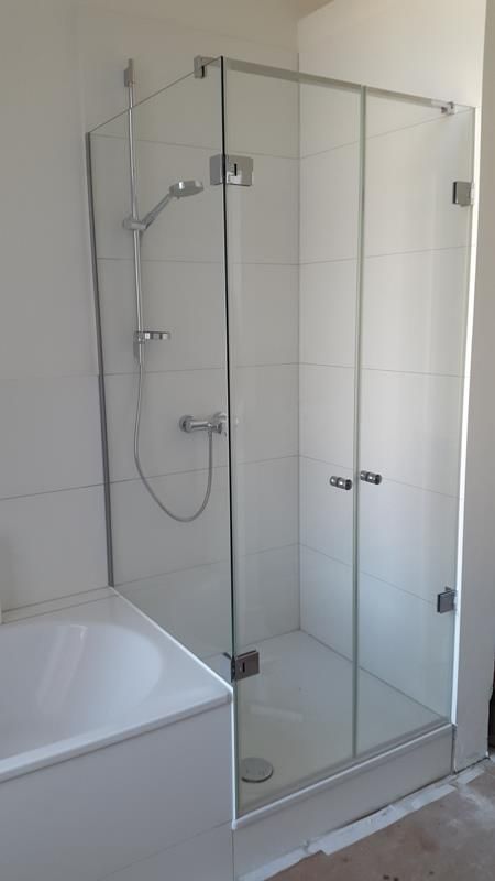 Ein Badezimmer mit Badewanne und Duschkabine mit Glastür.