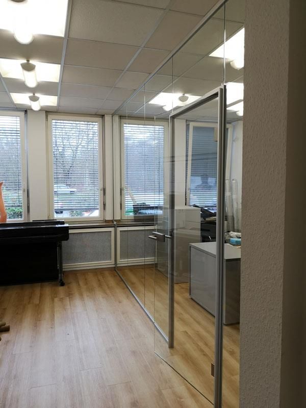 Ein großer Raum mit vielen Fenstern und einer Glastür.