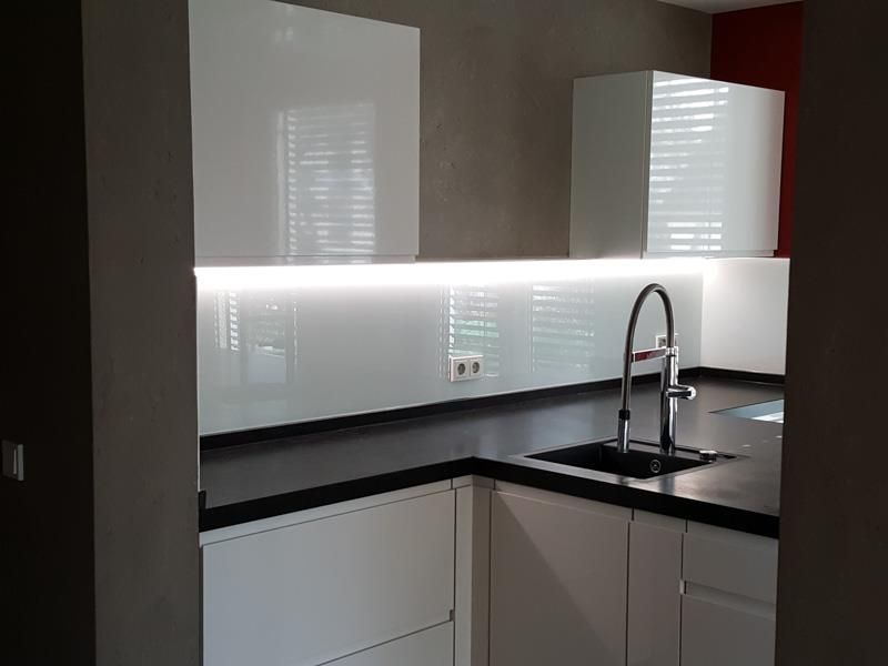 Eine Küche mit weißen Schränken, schwarzen Arbeitsplatten und einer Spüle.