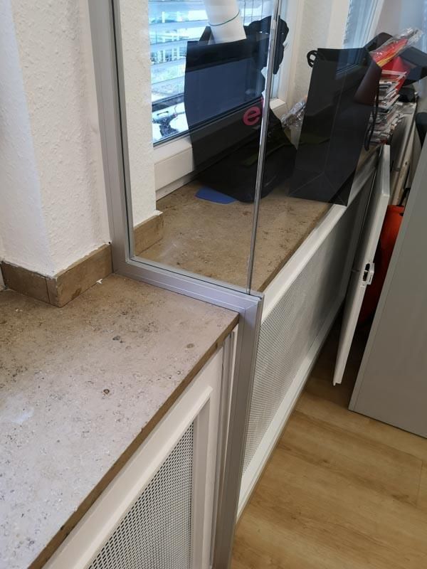 Ein Computermonitor steht auf einer Theke neben einem Fenster.