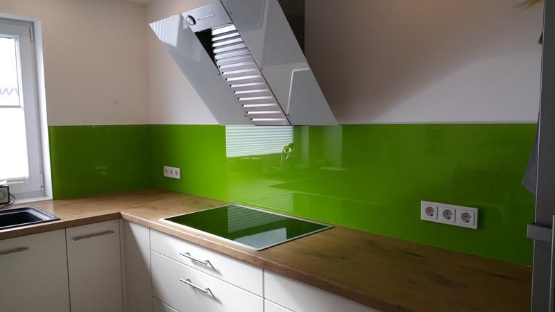 Eine Küche mit grüner Küchenrückwand und einem Herd mit Backofen.