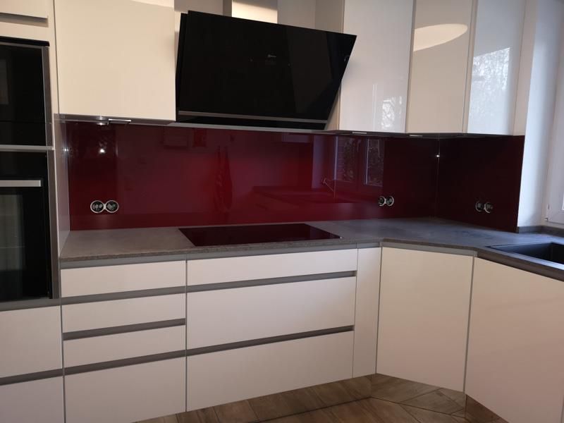 Eine Küche mit weißen Schränken und einer roten Küchenrückwand