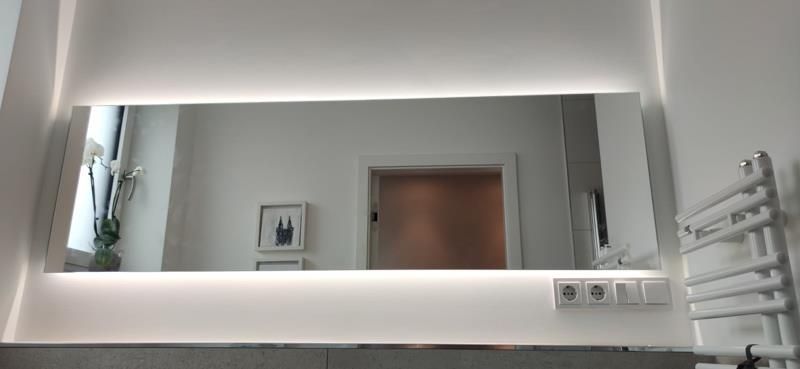 Ein Badezimmer mit großem Spiegel und Handtuchhalter.