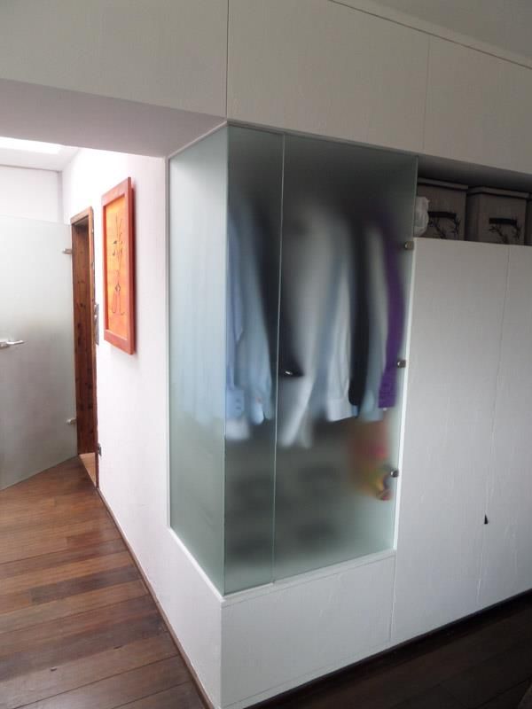 Eine Zimmerecke mit einer Glastür voller Kleidung