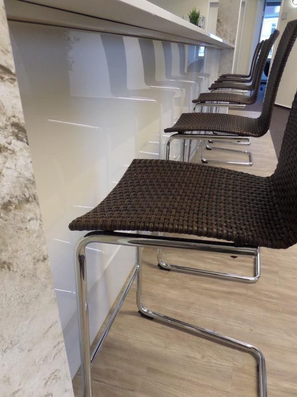 Neben einer Theke steht eine Stuhlreihe.