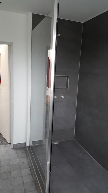 Ein Badezimmer mit ebenerdiger Dusche und Spiegel.