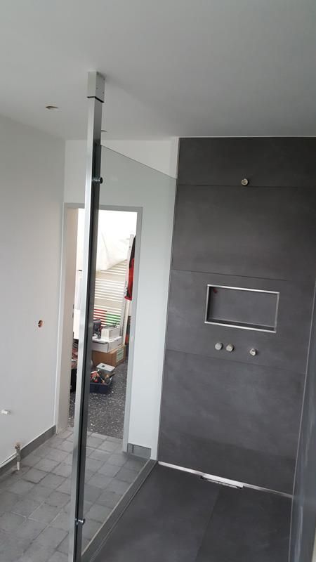 Ein Badezimmer mit ebenerdiger Dusche und einem Spiegel an der Wand.