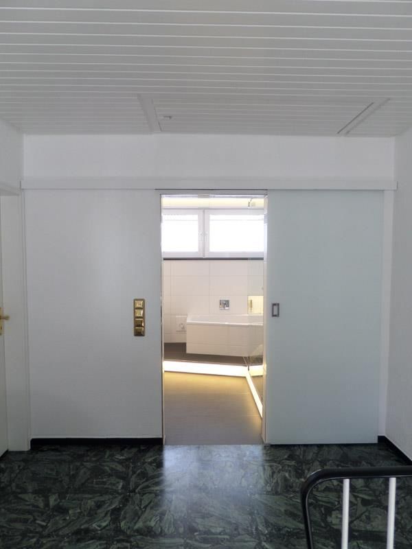 Ein Raum mit einer Schiebetür, die zu einem Badezimmer führt.