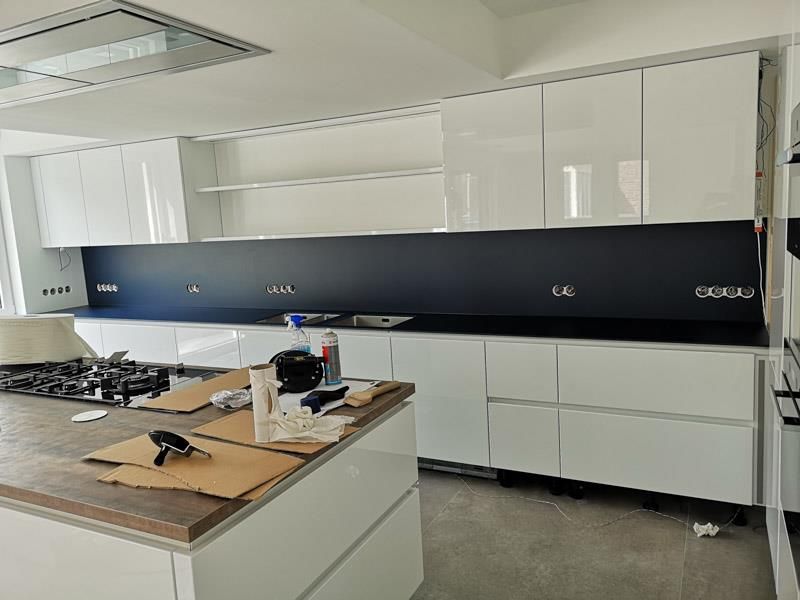 Eine Küche mit weißen Schränken und einer schwarzen Arbeitsplatte.