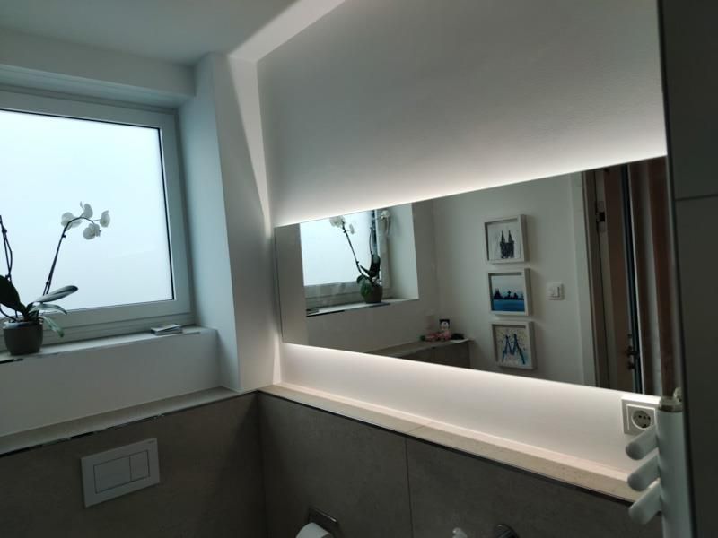 Ein Badezimmer mit großem Spiegel und Fenster