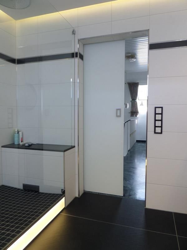 Ein Badezimmer mit weißen Fliesen und schwarzem Boden