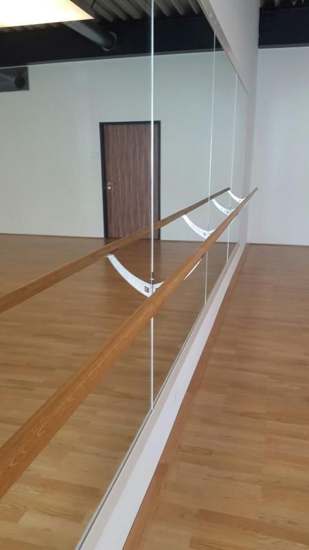 Ein Tanzstudio mit Holzboden und großem Spiegel.