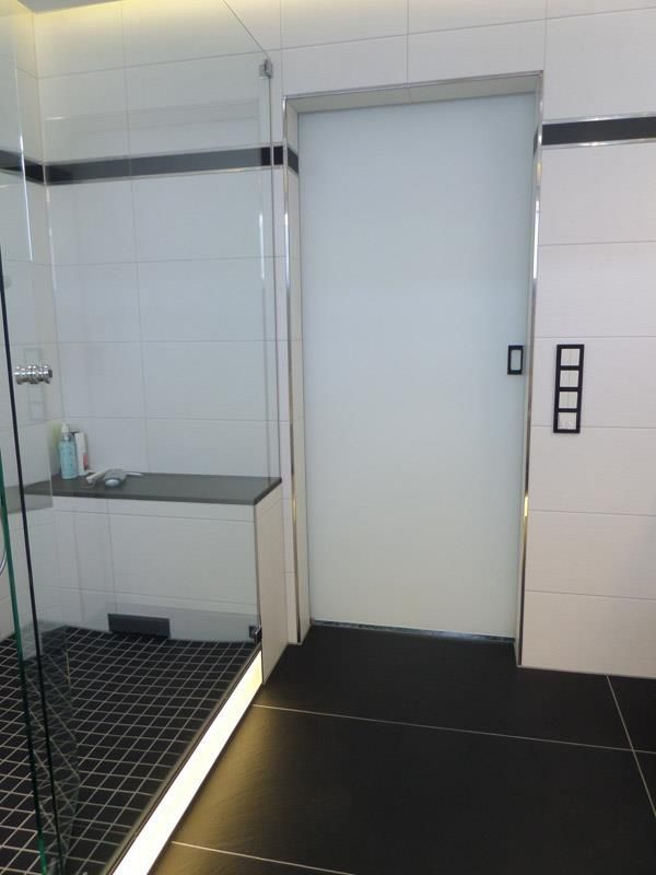 Ein Badezimmer mit schwarzen Fliesen und einer weißen Tür