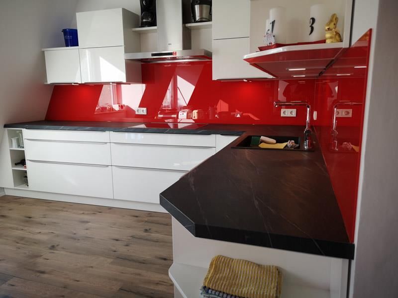 Eine Küche mit roten Schränken und einer schwarzen Arbeitsplatte