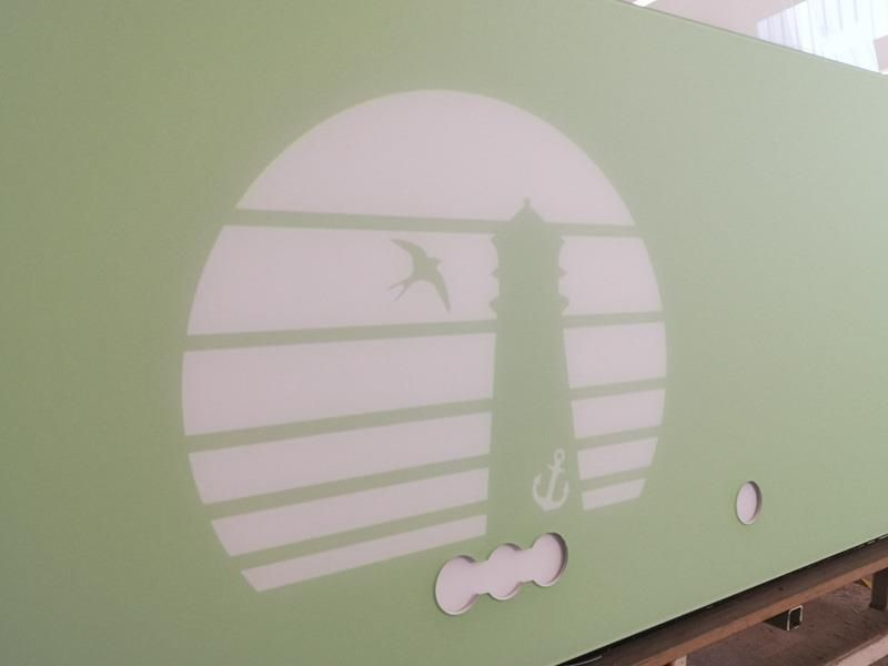 Eine grüne Wand mit der weißen Silhouette eines Leuchtturms darauf.