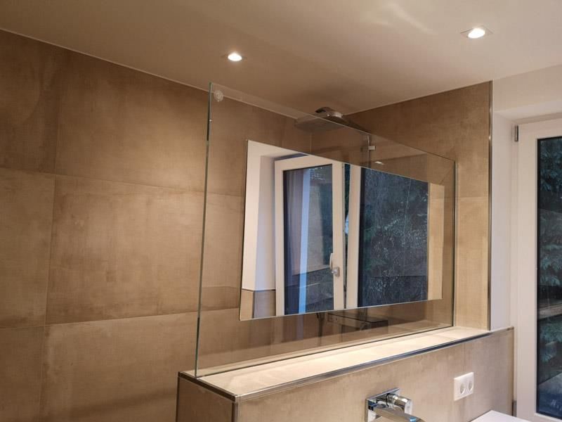 Ein Badezimmer mit ebenerdiger Dusche und großem Spiegel.