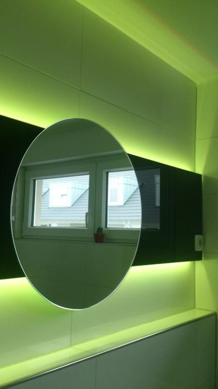 An einer Wand neben einem Fenster hängt ein runder Spiegel.