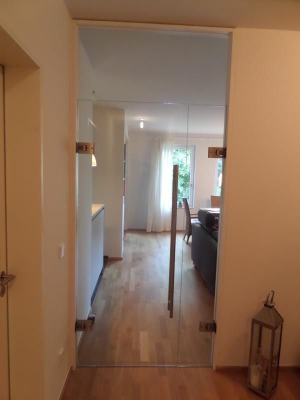 Ein Flur mit einer Glastür, die zu einem Wohnzimmer führt.