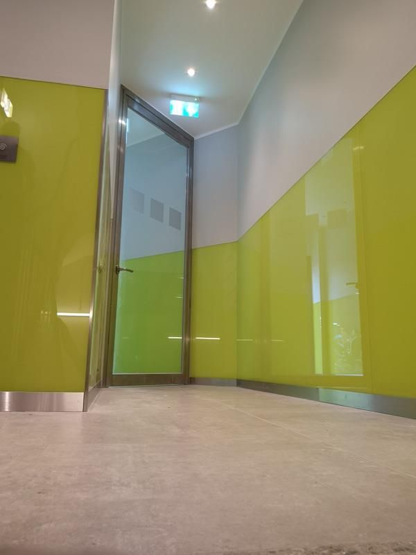 Ein Flur mit grünen Wänden und einer Glastür.