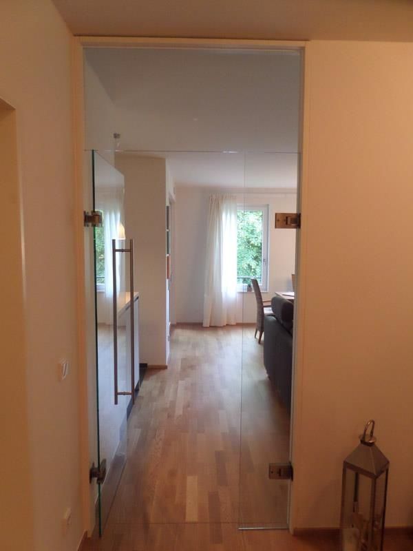 Ein Flur mit einer Glastür, die zum Wohnzimmer führt