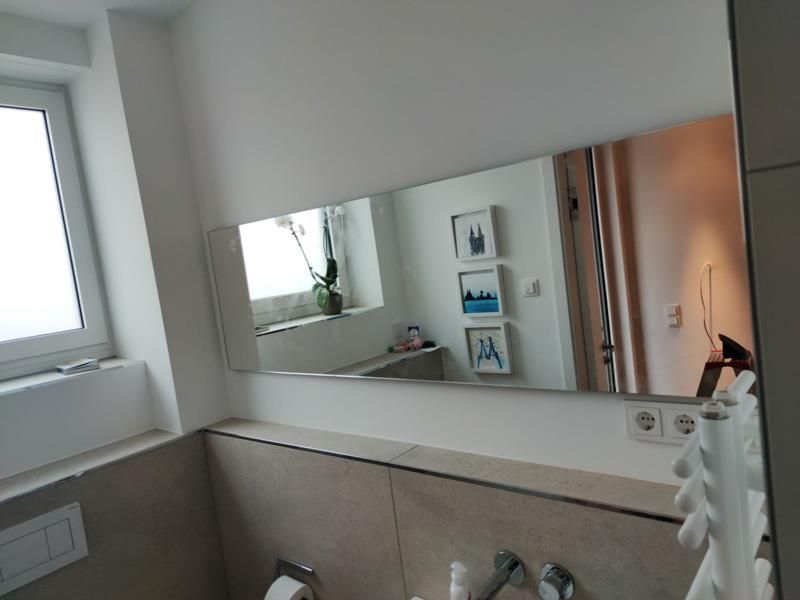 Ein Badezimmer mit großem Spiegel und Fenster