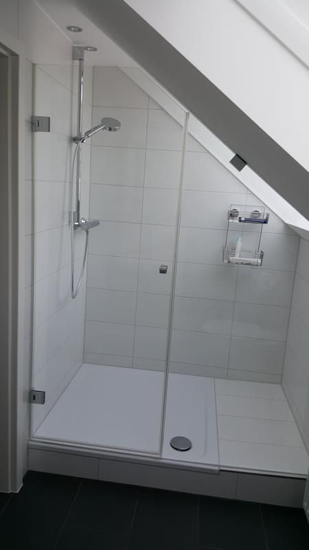 Ein Badezimmer mit Duschkabine unter einer Dachschräge.
