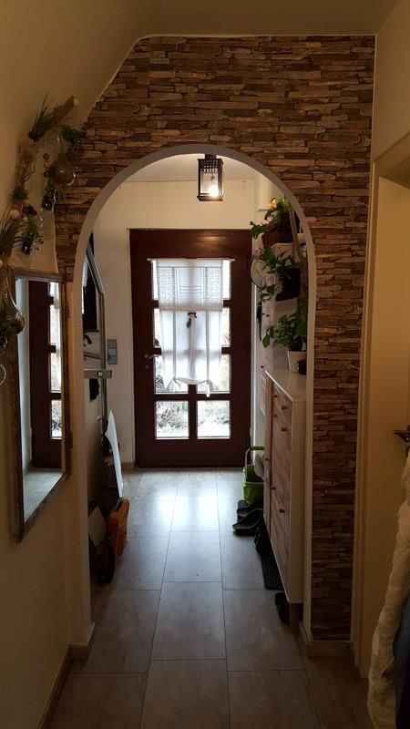 Ein Flur mit einer Ziegelwand und einer Holztür.