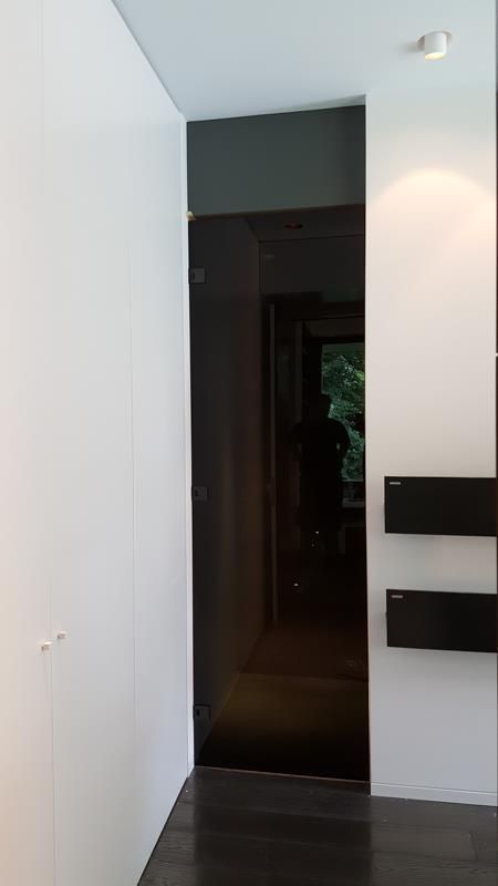 Ein Flur mit einer schwarzen Tür und weißen Wänden.