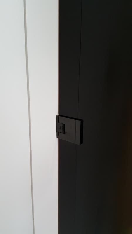 Eine Nahaufnahme einer schwarzen Tür mit einer weißen Wand dahinter.