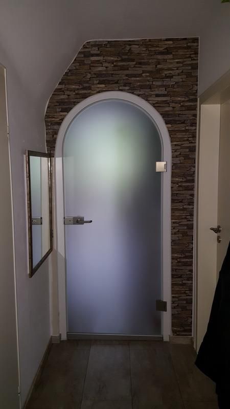 Ein Flur mit einer Glastür und einem Spiegel.