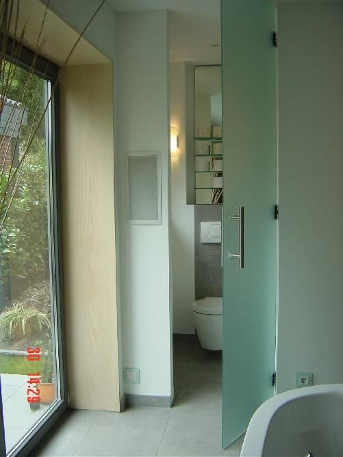 Ein Badezimmer mit einer Glastür, die zu einer Toilette führt