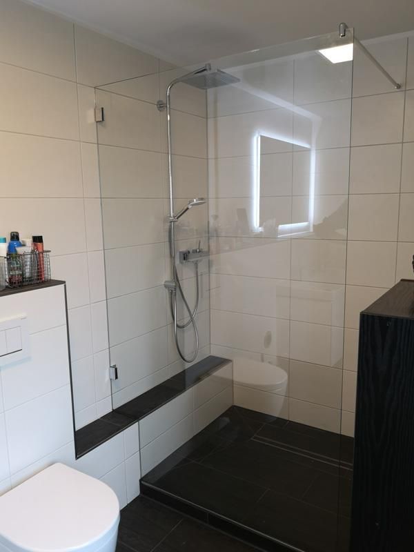 Ein Badezimmer mit Toilette, Dusche und Spiegel