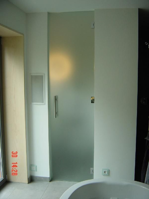 Ein Badezimmer mit Badewanne und Milchglastür