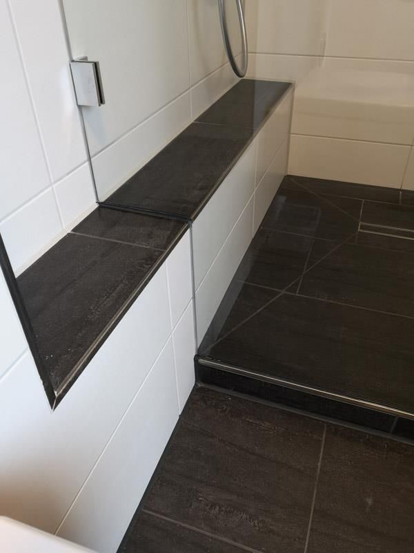 Ein Badezimmer mit schwarzem Fliesenboden und weißen Fliesen