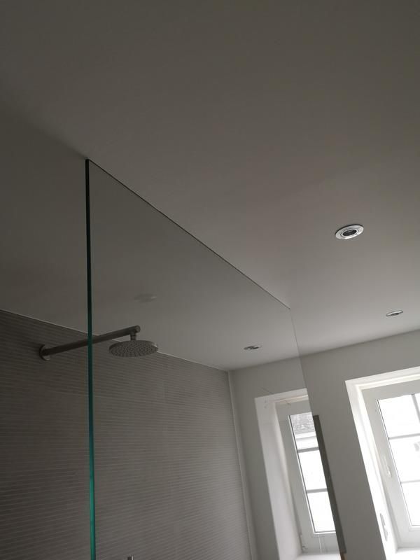 Ein Badezimmer mit einer Glasduschtür und einem Duschkopf.