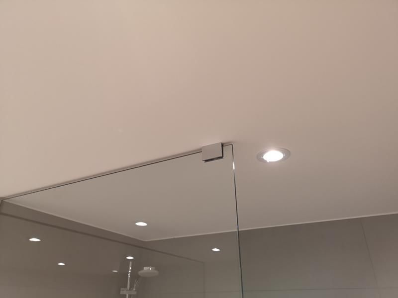 Ein Badezimmer mit einer Glasduschtür und einer weißen Decke.