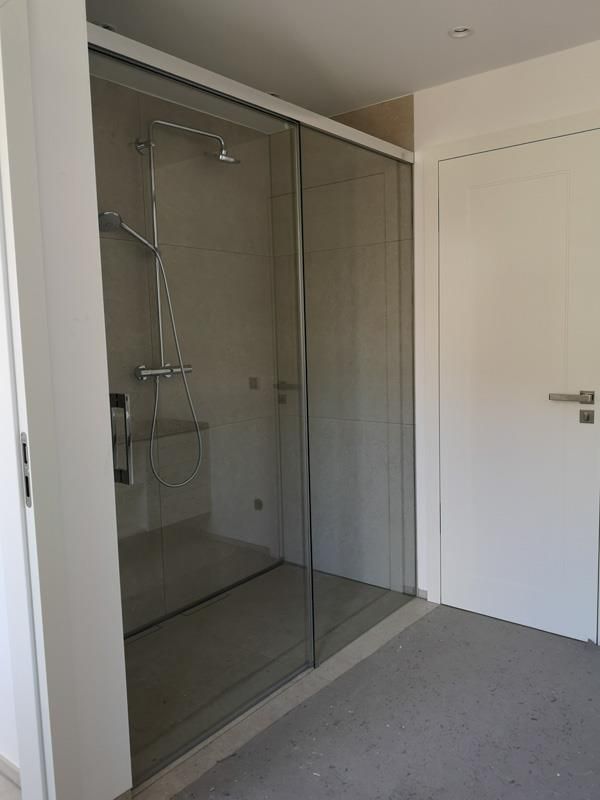 Ein Badezimmer mit ebenerdiger Dusche mit Glasschiebetüren.