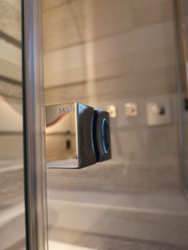 Eine Nahaufnahme eines Türgriffs an einer Glasduschtür.